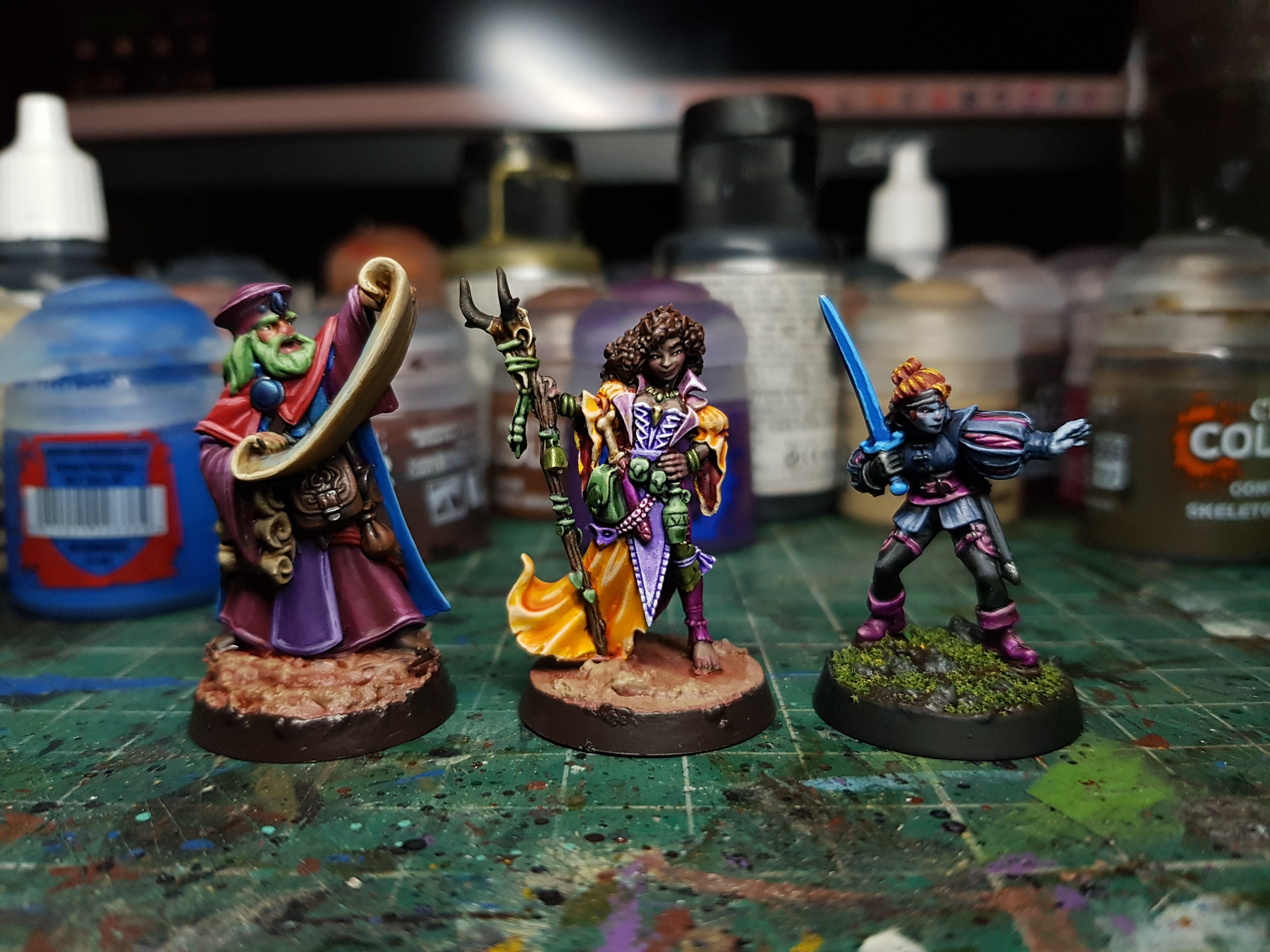 A photo of three painted models: a Reaper Minis wizard holding a big scroll, a Reaper Minis druid-y mage, and a North Star duellist.
